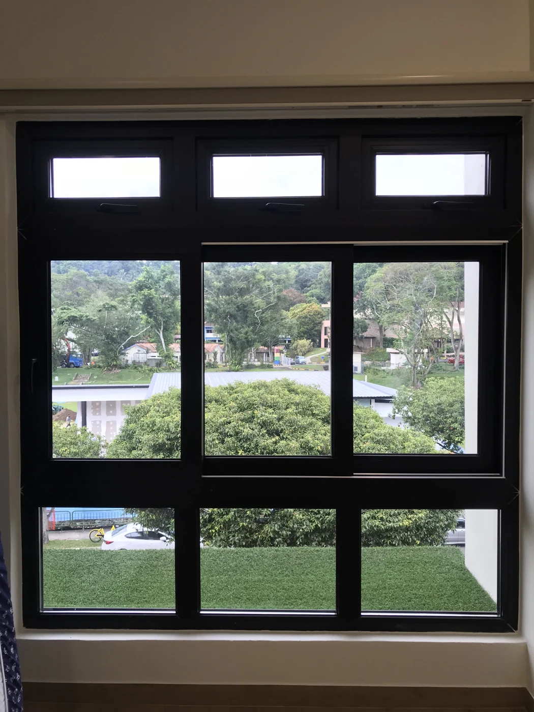 Dark aluminium windows with upper opening panels and a garden view in Singapore